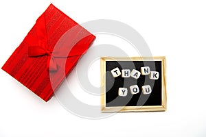 Top view of wooden cubes with thank you inscription on blackboard and gift box with ribbon