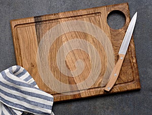 Top view of wooden cutting board,knife and striped linen napkin on the grey table.Free space