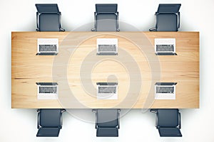 Top view of wooden meeting table with chairs and laptop