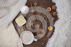 Top view on a wooden old table, where a white cup with cappuccino coffee, a cup with honey, nuts, a nut cracker and sweets are