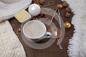 Top view on a wooden old table, where a white cup with cappuccino coffee, a cup with honey, nuts, a nut cracker and sweets are