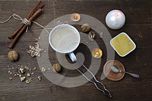 Top view on a wooden old table, where a white cup with cappuccino coffee, a cup with honey, nuts, a nut cracker and sweets are