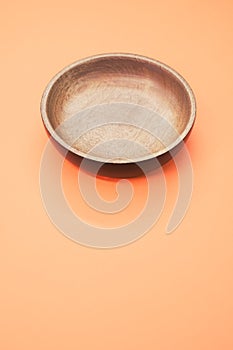 Top view of a wooden round tray on an orange background