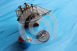 Top View Of Wooden Sailing Ship Mockup, Compass And Globe On Painted Sea Surface Stock Photo