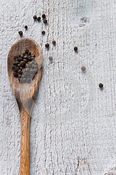 Top view of wooden spoon with black pepper