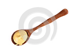 Top view of wooden spoon with Dijon mustard isolated on white background.