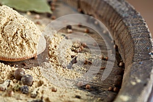 Top view of a wooden spoon full of curry on wooden barrel background, selective focus.