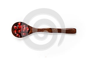 Top view. A wooden spoon with seeds in it. Wooden spoon with pomegranate seeds isolated on a white background. Fruit pomegranate.