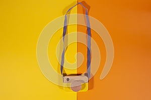 Top view of wooden vintage camera on yellow and orange paper background. World Photography Day concept
