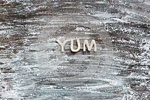 Top view of word yum made from cookie dough with flour