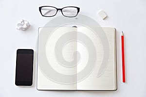 Top view of a working desk with open blank notebook