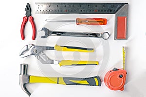 Top view of Working tools,wrench,socket wrench,hammer,screwdriver,plier,electric drill,tape measure,machinist square on white