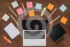 top view of workplace with arranged textbooks post it and laptop with blank