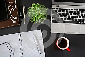 Top view of workplace with laptop and other items on black desktop