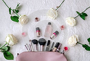 Top view, workspace, bag for cosmetic brushes, makeup and flowers