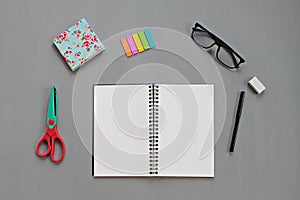 Top view of workspace desk with blank notebook and office stationery set on gray background