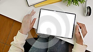 Top view workspace with a female using stylus pen and tablet. tablet white screen mockup