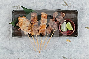 Top view of Yakitori Japanese-Style Grilled Chicken Skewers with chicken and internal organ served with sliced lime.