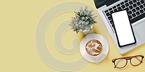 Top view, Yellow Office desk with laptop computer, Blank screen smart phone, cup of coffee and eyeglass copy space, Mock up