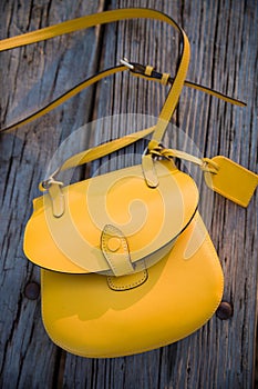 Top view on yellow purse on the old wooden table background. Nice woman`s bag