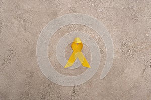 Top view of yellow ribbon on grey background, international childhood cancer day concept. photo
