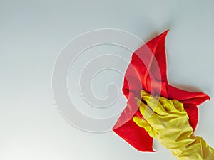 Top view of yellow rubber glove hand and red cotton rug wipe cleansing a white surface in a house, doing chores for more cleanse