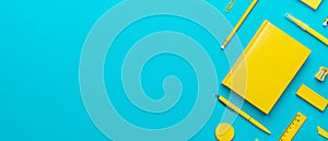 Top view of yellow stationery over turquoise blue background with copy space