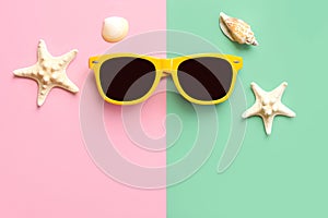 Top view of yellow sunglasses, starfish and seashells with copy space for text. Summer vacation concept