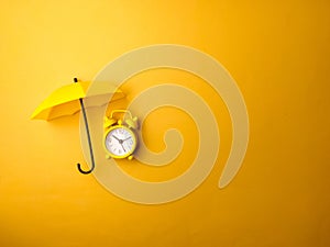 Top view yellow umbrella and yellow alarm clock on a yellow background