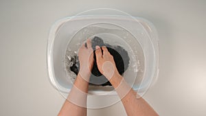 TOP VIEW: Young adult man hand wash a clothes in a pelvis