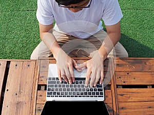 Top view of young Asian man using computer laptop at outdoors.