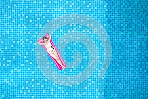 Top view of young asian woman in swimsuit on the pink air mattress in the swimming pool