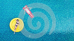 Top view of young asian woman in swimsuit on the pink donut lilo in the swimming pool