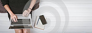 Top view of a young asian woman using laptop computer sitting on wooden floor at home , work from home concept