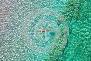 Top view. Young beautiful naked woman in a hat swimming in sea water on sand beach. Drone, copter photo. Summer vacation. View fro