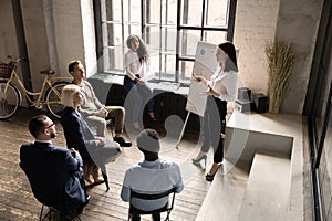 Top view young business coach presenting statistics on flip chart