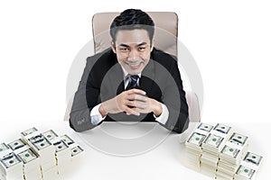 Top view of young businessman and two big piles of money on desk