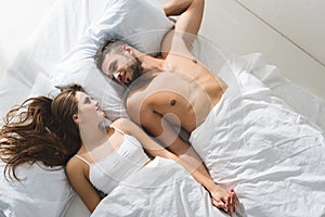 top view of young couple holding hands in bed