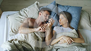 Top view of young couple lying in bed upset and argue each other