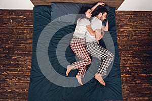 Top view. Young couple in pajamas sleeps close together on bed at home.