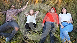 Top view of young couple of parents with little children lying on grass at field and spending time together at nature