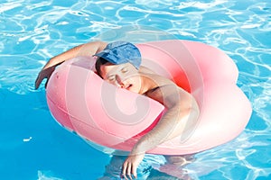 Top view of young drunk guy swim with pink circle in pool. drunk guy on vacation in the hotel photo