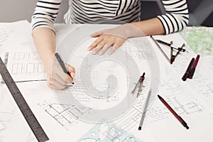 Top view of young good-looking freelance engineer wearing formal striped clothes working at comfortable bif table,making