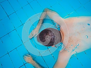 Top view of a young handsome man diving underwater in a swimming