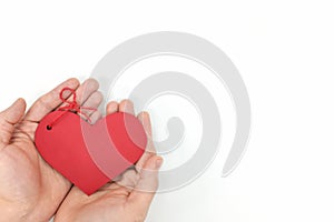 Top view of young male cupped hands holding a red heart shape tag in white background. Non-materialistic love is the best gift.
