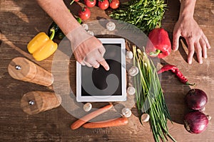 top view of young man cooking with tablet and pointing at blank screen