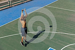 Top view of young man, male basketball player playing basketball at street public stadium, sport court or palyground