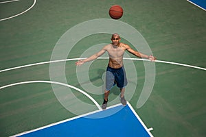 Top view of young man, male basketball player playing basketball at street public stadium, sport court or palyground