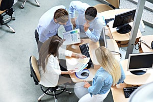 Top view of young modern colleagues in smart casual wear working together while spending time in the office. photo