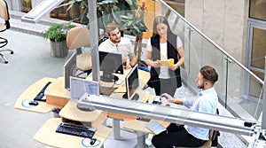 Top view of young modern colleagues in smart casual wear working together while spending time in the office.